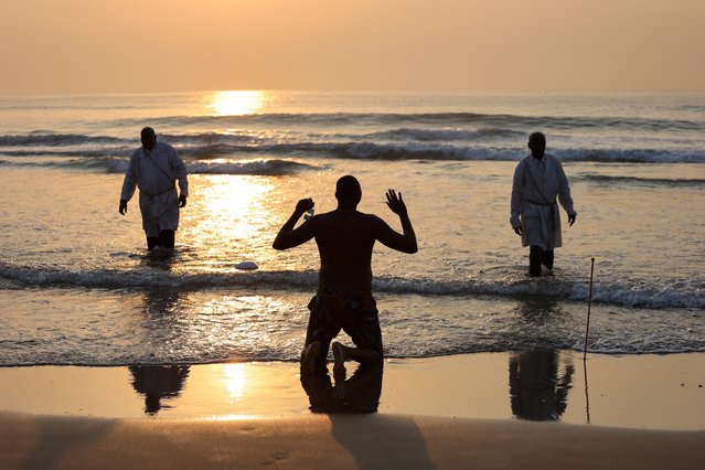 A man raises his hands in prayer after members of Zion Christian Church performed baptisms, on the day the Electoral Commission of South Africa officially announces the results of the recent national election, at North Beach in Durban, South Africa on June 2, 2024. (Photo by Alaister Russell/Reuters)