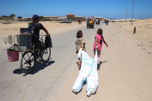 Palestinian children use a hazmat suit to transport belongings as they flee the area of Tel al-Sultan in Rafah in the southern Gaza Strip on May 30, 2024, amid the ongoing conflict between Israel and the militant group Hamas. (Photo by Eyad Baba/AFP Photo)
