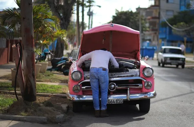 A man repairs a vintage American car on the side of the road in Havana, Cuba on March 26, 2019. (Photo by Phil Noble/Reuters)
