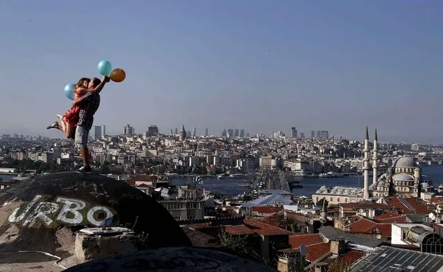 A couple kiss each other as they pose for a friend taking photographs, backdropped by Istanbul's skyline, Thursday, July 9, 2015. Istanbul is a thoroughly modern place, but it traces its roots back to 660 B.C. It's the former seat of the opulent Byzantine and Ottoman empires and is divided into European and Asian sides by the Bosphorus Strait, offering a wealth of history and stunning scenery. (Photo by Emrah Gurel/AP Photo)