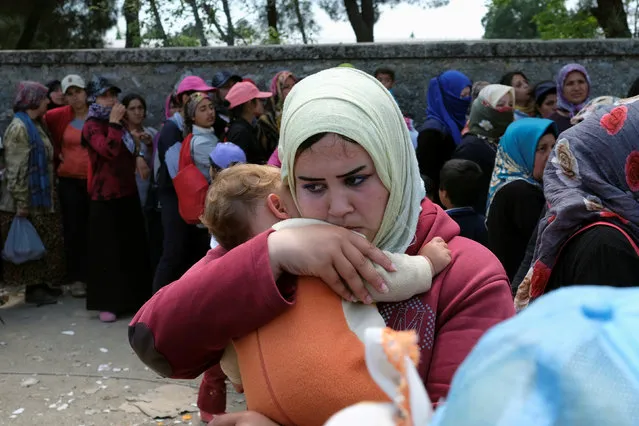 A woman holds a baby after clashes between migrants happened at a makeshift camp at the Greek-Macedonian border near the village of Idomeni, Greece, May 10, 2016. (Photo by Marko Djurica/Reuters)