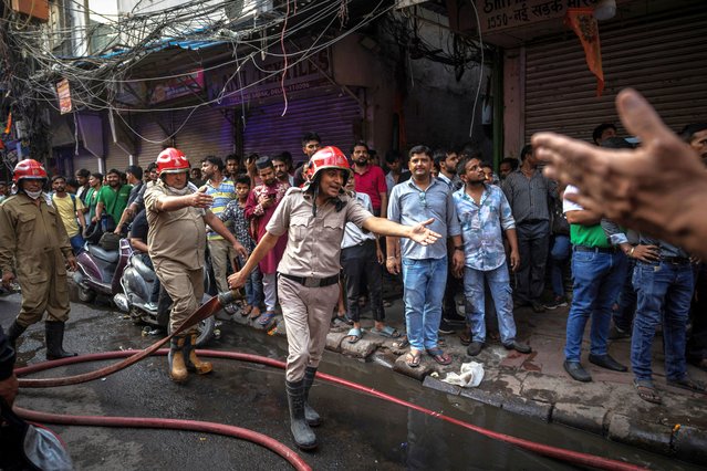 Firefighter Rajesh Dabhas, 43, pulls a water pipe as he tries to extinguish a fire in some textile shops at a market area in the old quarters of Delhi, India, June 13, 2024. (Photo by Adnan Abidi/Reuters)