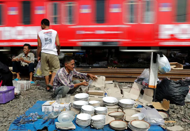 A vendor (R) sells crockery and utensils as a commuter train passes by in Jakarta, Indonesia, May 4, 2016. (Photo by Reuters/Beawiharta)
