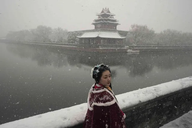 A woman dressed in traditional period costume pose for photos near the Forbidden City as it snows on Friday, March 18, 2022, in Beijing. (Photo by Ng Han Guan/AP Photo)