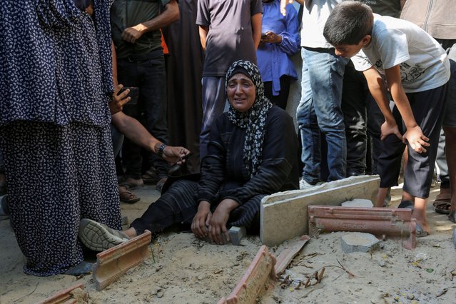 A relative of a Palestinian killed during the Israeli military offensive and buried earlier at al-Amal Hospital, reacts next to their grave as preparations are made to exhume them for reburial in a cemetery, in Khan Younis in the southern Gaza Strip on July 18, 2024. (Photo by Hatem Khaled/Reuters)