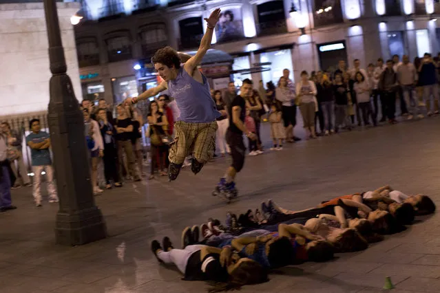 A roller skater jumps over eight people lying on the ground, at Sol square in the center of Madrid, Spain, Tuesday, May 6, 2014. (Photo by Emilio Morenatti/AP Photo)