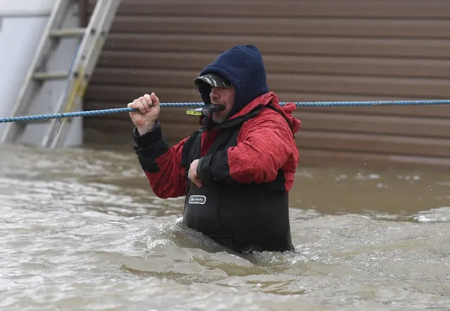 A resident holds his phone in his teeth as he navigates deep waters on Voisine Road in Rockland, Ont., about 40 kilometres east of Ottawa, Sunday, May 7, 2017, as rising levels on the Ottawa River and heavy rains continue to cause flooding. (Photo by Justin Tang/The Canadian Press via AP Photo)