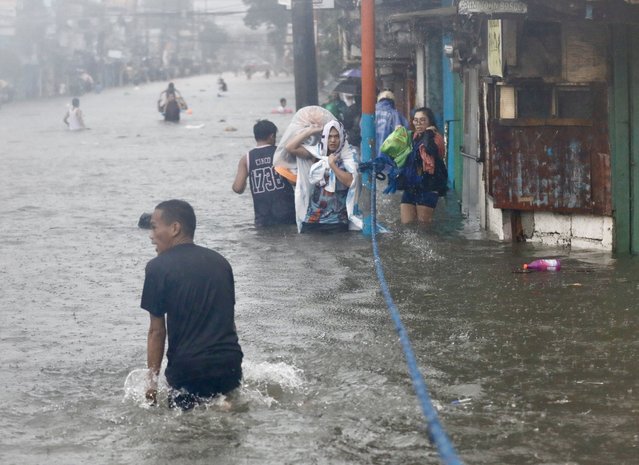 Residents carrying belongings wade in rising floodwaters in Marikina city, Metro Manila, Philippines, 24 July 2024. (Photo by Francis R. Malasig/EPA/EFE)