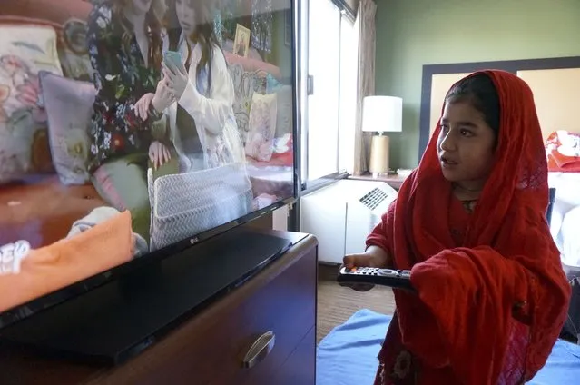 Sana Sultani, 8, watches children's programming on television in the motel room she shares with her parents and five siblings in El Paso, Texas, on Saturday, March 26, 2022. The Sultanis, one family among thousands of Afghans evacuated to the United States as the Taliban regained power last summer, moved into a duplex just in time to celebrate their first Muslim holy month of Ramadan in the U.S. (Photo by Giovanna Dell'Orto/AP Photo)