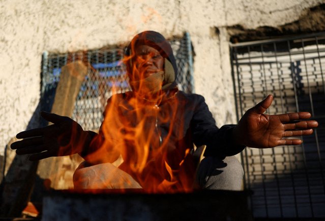 Dumisani Cele warms himself with a brazier, as a series of cold fronts hits parts of the country, in the south of Johannesburg, South Africa on July 9, 2024. (Photo by Siphiwe Sibeko/Reuters)