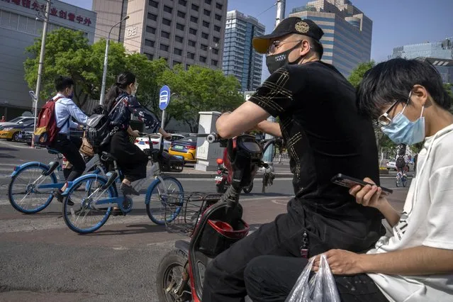 Commuters wearing face masks wait at an intersection in the central business district in Beijing, Thursday, May 5, 2022. (Photo by Mark Schiefelbein/AP Photo)