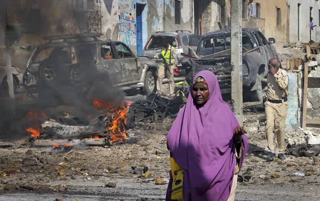 A Somali woman walks past the scene of a suicide car bomb attack on a police station in Mogadishu, Somalia Thursday, June 22, 2017. A number of people are dead and several others wounded in the blast in Somalia's capital, police said Thursday, adding that the bomber was trying to drive into the police station's gate but detonated against the wall instead. (Photo by Farah Abdi Warsameh/AP Photo)