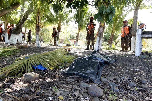 Soldiers stand next to the body of a man who went missing during heavy rains and was found during a search in Punta Caimanes, in the Izabal region, near Guatemala City, August 8, 2015. (Photo by Josue Decavele/Reuters)