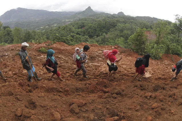 Villagers make their way at an area affected by a landslide in Sukajaya, West Java, Indonesia, Sunday, January 5, 2020. Landslides and floods triggered by torrential downpours have left dozens of people dead in and around Indonesia's capital, as rescuers struggled to search for people apparently buried under tons of mud, officials said Saturday. (Photo by Ar Rayyan/AP Photo)
