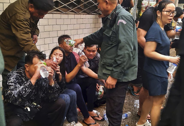 In this photo provided by Cambodia's Fresh News, victims of a fire receive water from police officers  near a Cambodia-Thai international border gate in Poipet, west of Phnom Penh, Cambodia, Wednesday, December 28, 2022. A fire burning through the Grand Diamond City Casino and Hotel has killed multiple people and injured dozens of others, police said Thursday, and neighboring Thailand sent firetrucks to help fight the blaze in a bustling border region. (Photo by Fresh News via AP Photo)