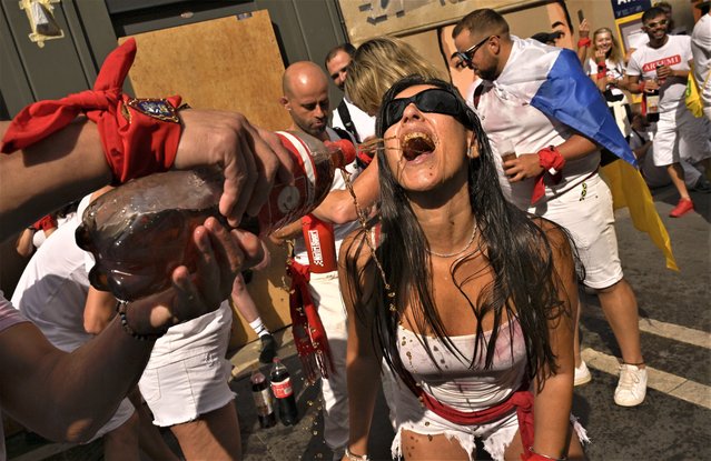 A reveller drinks wine while waiting for the launch of the “Chupinazo” rocket, to mark the official opening of the 2023 San Fermín fiestas in Pamplona, Spain, Thursday, July 6, 2023. (Photo by Alvaro Barrientos/AP Photo)