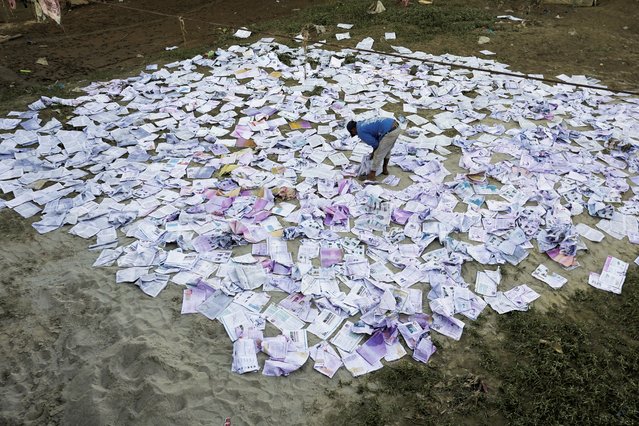 A man dries books which soaked water during the deadly flood following heavy rainfall along the bank of Bagmati River following heavy rains, in Kathmandu, Nepal on October 2, 2024. (Photo by Navesh Chitrakar/Reuters)