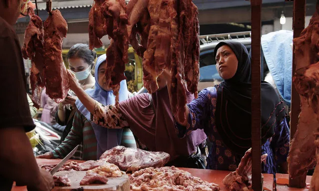 Muslim women shop for meat in preparation of the upcoming Eid al-Fitr holiday that marks the end of the holy fasting month of Ramadan, at a market in Jakarta, Indonesia, Friday, June 23, 2017. (Photo by Achmad Ibrahim/AP Photo)