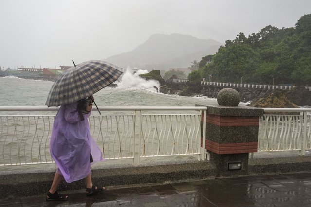 A photographer walks along the coast at Sizihwan beach in Kaohsiung on October 2, 2024. - Taiwan shut down schools and closed its financial markets on October 2 as Typhoon Krathon pounded its south and east with torrential rains and winds ahead of its expected landfall. (Photo by Walid Berrazeg/AFP Photo)