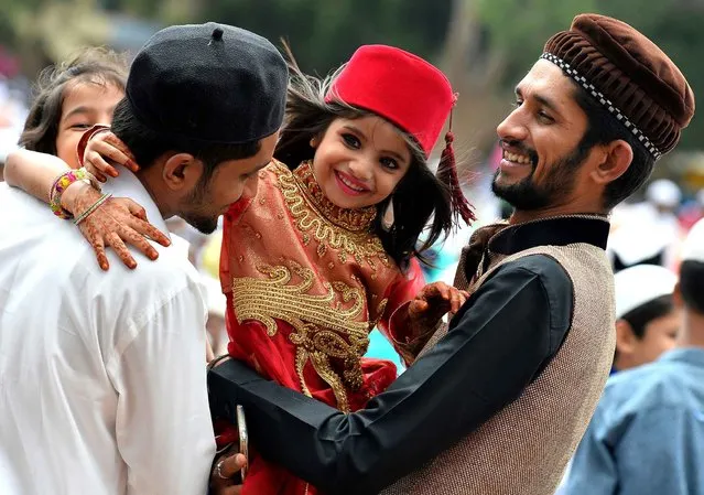 A young Indian Muslim girl hugs her elders after Eid-al-Fitr prayers at Chamrajpet Idgah Maidan in Bangalore on July 7, 2016. The three-day festival, which begins after the sighting of a new crescent moon, marks the end of the fasting month of Ramadan during which devout Muslims abstain from food and drink from dawn to dusk. (Photo by Manjunath Kiran/AFP Photo)