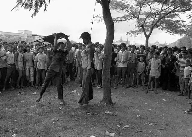 A member of a Thai political faction strikes at the lifeless body of a hanged student outside Thammasat University in Bangkok October 6, 1976. Police stormed the university after students demanded expulsion of a former military ruler and barricaded themselves in the school. The picture won the Pulitzer Prize in 1977. (Photo by Neal Ulevich/AP Photo)