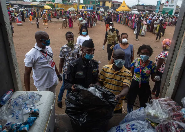 A police officer assists volounteers organizing food parcels at a food distribution organized by the government to help residents to cope with the lockdown at the Agbogbloshie market in Accra, Ghana. April 4th 2020. Ghana has announced a two-week lockdown in the country's two main regions of Accra and Kumasi. The move came as the authorities reported 137 confirmed cases, including four deaths. (Photo by Nipah Dennis/AFP Photo)
