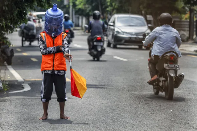 A resident uses face shields made from used mineral water containers while working on the streets of Yogyakarta City, Indonesia on April 16, 2020. This face shield aims to prevent contracting from coronavirus while working outside the home. (Photo by Nuryanto/Opn Images/Barcroft Media via Getty Images)