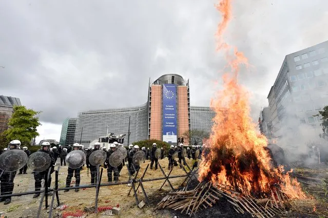 Police officers stand guard as farmers and dairy farmers from all over Europe take part in a demonstration outside a European Union agricultural ministers' emergency meeting at the EU Council headquarters in Brussels, Belgium September 7, 2015. (Photo by Eric Vidal/Reuters)