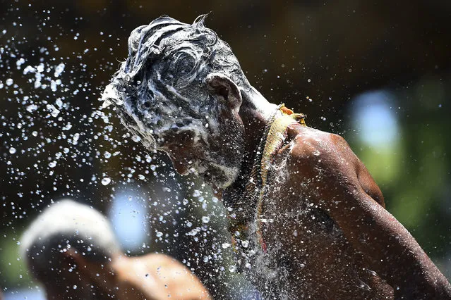 Porters wash themselves as police splash water with canon vehicles in the capital Colombo on April 17, 2020, before taking them to a quarantine centre. (Photo by Ishara S. Kodikara/AFP Photo)