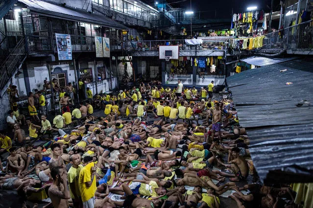 Inmates sleep on the ground of an open basketball court inside the Quezon City jail at night in Manila in this picture taken on July 21, 2016. There are 3,800 inmates at the jail, which was built six decades ago to house 800, and they engage in a relentless contest for space. Men take turns to sleep on the cracked cement floor of an open-air basketball court, the steps of staircases, underneath beds and hammocks made out of old blankets. (Photo by Noel Celis/AFP Photo)
