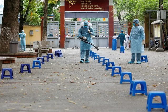 Health workers wearing protective suits spray disinfectant as a preventive measure against coronavirus at a makeshift rapid testing center for coronavirus disease, in Hanoi, Vietnam on March 31, 2020. (Photo by Reuters/Kham)