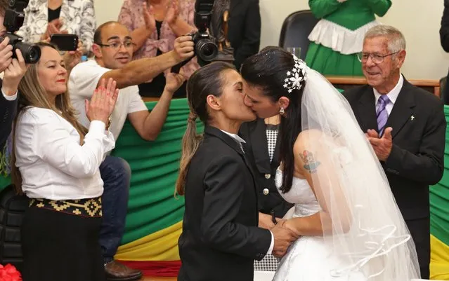Solange Ramires (R) and Sabriny Benites, the only same-s*x couple of 30 couples being married, kiss after they were wed by a judge presiding over the joint ceremony in the Forum of Santana do Livramento, September 13, 2014. (Photo by Edison Vara/Reuters)