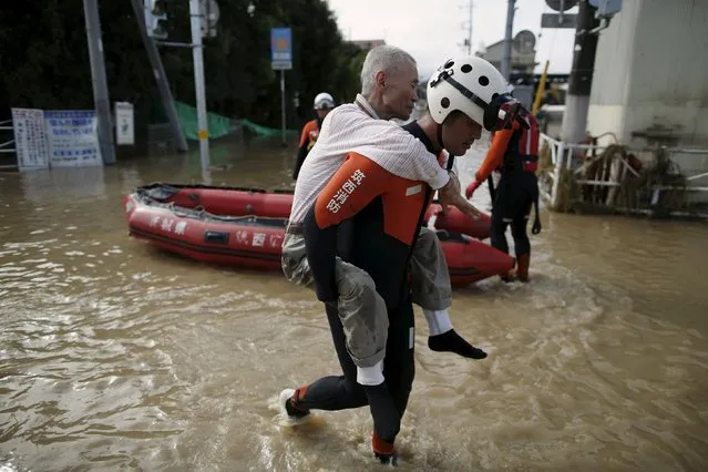 An elderly man is rescued by a firefighter at a residential area flooded by the Kinugawa river, caused by typhoon Etau in Joso, Ibaraki prefecture, Japan, September 11, 2015. (Photo by Issei Kato/Reuters)