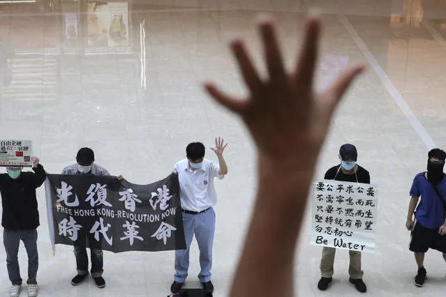 Protesters gesture with five fingers, signifying the “Five demands – not one less” in a shopping mall during a protest against China's national security legislation for the city, in Hong Kong, Friday, May 29, 2020. The British government says t it will grant hundreds of thousands of Hong Kong residents greater visa rights if China doesn't scrap a planned new security law for the semi-autonomous territory. U.K. Foreign Secretary Dominic Raab said about 300,000 people in Hong Kong who hold British National (Overseas) passports will be able to stay in Britain for 12 months rather than the current six. (Photo by Kin Cheung/AP Photo)