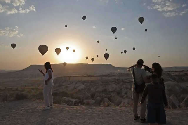 People watch as sight-seeing hot air balloons launch in Goreme Historical National Park, east of Nevesehir (Neapolis) in the province of the same name in central Turkey's historical Cappadocia (Kapadokya) region on August 24, 2022. (Photo by Omar Haj Kadour/AFP Photo)