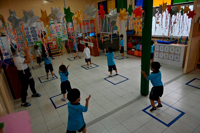 Students in a kindergarten class stand inside social distancing markings on the floor on the first day of the reopening of the International Pioneers School in Bangkok on June 16, 2020, following its temporary closure due to the COVID-19 coronavirus epidemic. Some schools in Thailand have reopened as they adopted preventive measures such as social distancing and regular disinfection to halt the spread of the virus. (Photo by Romeo Gacad/AFP Photo)