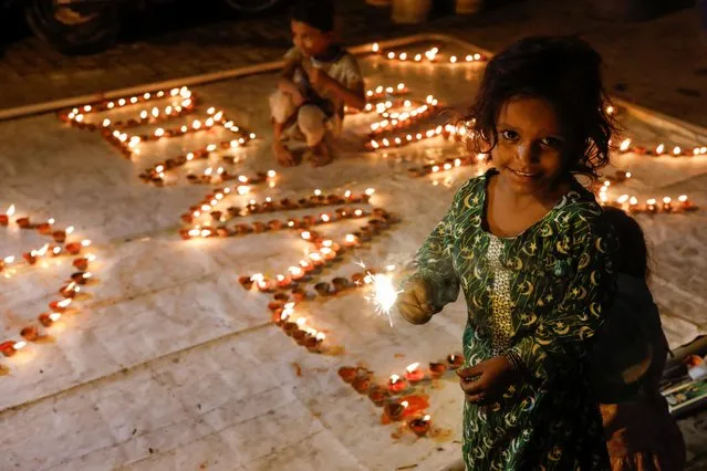 A girl waves a burning sparkler during Diwali, the Hindu festival of lights, in Karachi, Pakistan on October 24, 2022. (Photo by Akhtar Soomro/Reuters)
