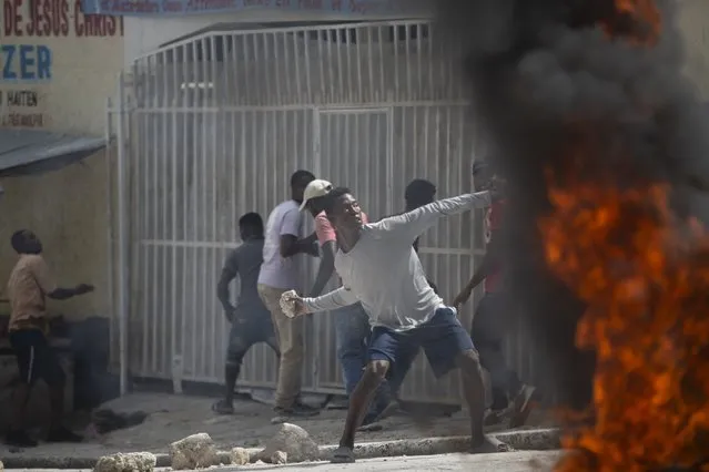 A protester throws a stone at police during a protest over the death of journalist Romelo Vilsaint, in Port-au-Prince, Haiti, Sunday, October 30, 2022. (Photo by Joseph Odelyn/AP Photo)