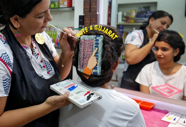 A woman gets an Electronic Voting Machine (EVM) painted in her hair at a parlor to promote voting ahead of Gujarat state assembly election in Ahmedabad, India, December 7, 2017. (Photo by Amit Dave/Reuters)