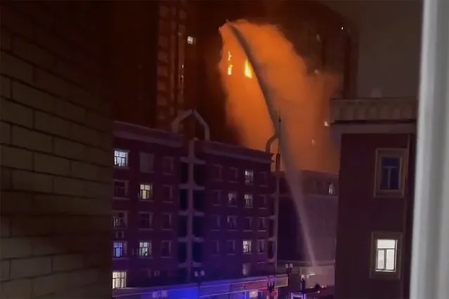 In this image taken from video, firefighters spray water on a fire at a residential building in Urumqi in western China's Xinjiang Uyghur Autonomous Region, Thursday, November 24, 2022. A fire in an apartment building in northwestern China's Xinjiang region has killed several people and injured others, authorities said Friday, in the second major fire accident in the country this week. (Photo by AP Photo/Stringer)