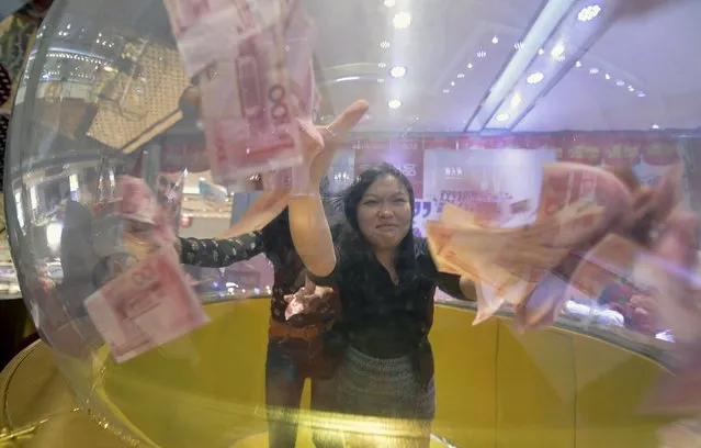Participants try to catch 100 yuan banknotes flying inside a dome during a promotional event of a jewelry store in Nanjing, Jiangsu province, China, September 23, 2015. The contestants were required to catch as many banknotes as they could in 20 seconds, and the winner would be awarded with the money he or she caught, local media reported. (Photo by Reuters/Stringer)