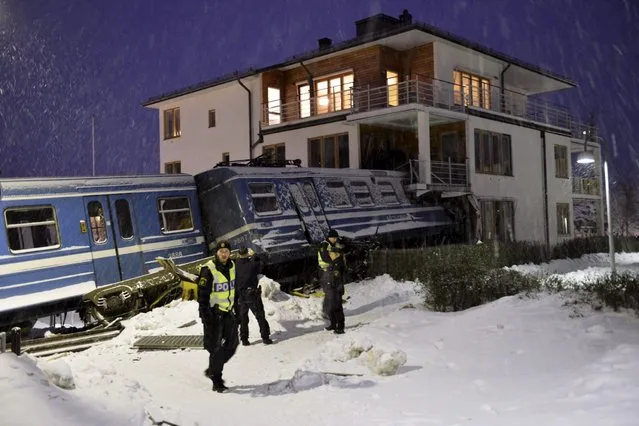 Police officers stand around a local train that derailed and crashed into a residential building in Saltsjobaden outside Stockholm in this picture taken by Scanpix Sweden January 15, 2013. According to local media, a spokesman from Arriva, the company that operates the train line, says the train was stolen by a domestic cleaner, who stole the train for unknown reasons. The cleaner was taken to a hospital after the crash. No residents in the building were injured. (Photo by Jonas Ekstromer/Reuters/Scanpix Sweden)