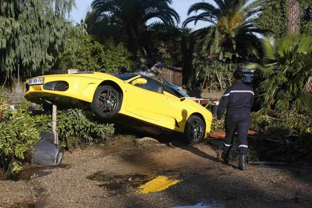 A French fireman walks near a damaged Ferrari after flooding caused by torrential rain in Biot, France, October 4, 2015. (Photo by Eric Gaillard/Reuters)
