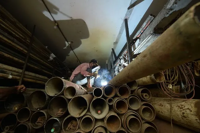 A man welds a steel pipe at a workshop in Dhaka on July 27, 2020. (Photo by Munir Uz Zaman/AFP Photo)