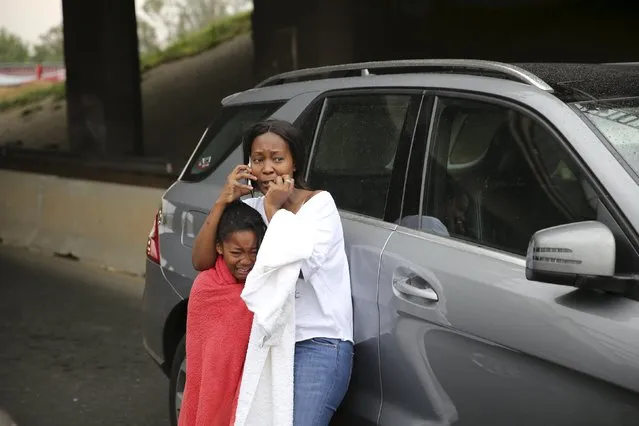 A women and a child react after they narrowly escaped being trapped when a bridge collapsed on the M1 highway near a busy offramp leading to Sandton, South Africa October 14, 2015. (Photo by Siphiwe Sibeko/Reuters)
