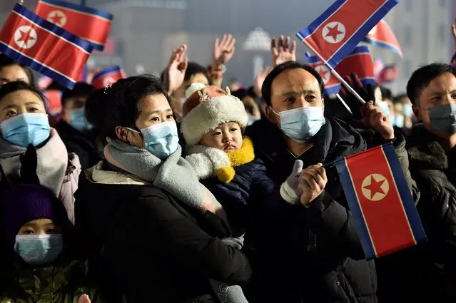 In this photo taken late on December 31, 2022, people attend a flag raising ceremony during celebrations for the new year on Kim Il Sung Square in Pyongyang. (Photo by Kim Won Jin/AFP Photo)