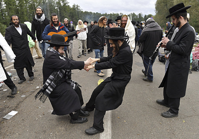 Hasidic Jewish pilgrims dance as they gather in front of Ukrainian border guards at the checkpoint Novaya Guta near Novaya Guta, Belarus, Friday, September 18, 2020. Ukrainian officials say that thousands of Hasidic Jewish pilgrims stuck on the Ukrainian border due to coronavirus restrictions have started turning back. About 2,000 ultra-Orthodox Jewish pilgrims traveled to Belarus's border with Ukraine in hope of traveling to the Ukrainian city of Uman to visit the grave of an important Hasidic rabbi who died in 1810, Nachman of Breslov. (Photo by AP Photo/Stringer)