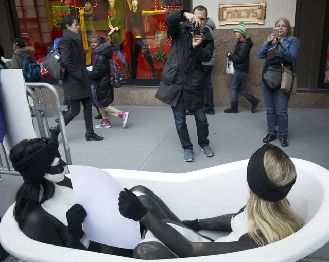 People stop to take pictures of naked women from the People for the Ethical Treatment of Animals (PETA) painted to resemble orca whales as they protest outside Macy's department store in New York, November 20, 2014. Members of PETA demonstrated on Thursday against this year's Macy's Thanksgiving Day Parade that will include a SeaWorld float. (Photo by Brendan McDermid/Reuters)