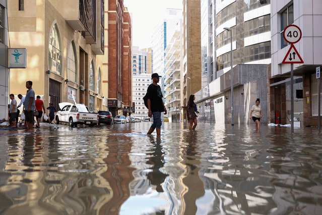 People walk through flood water caused by heavy rains, in Dubai, United Arab Emirates, on April 17, 2024. (Photo by Amr Alfiky/Reuters)