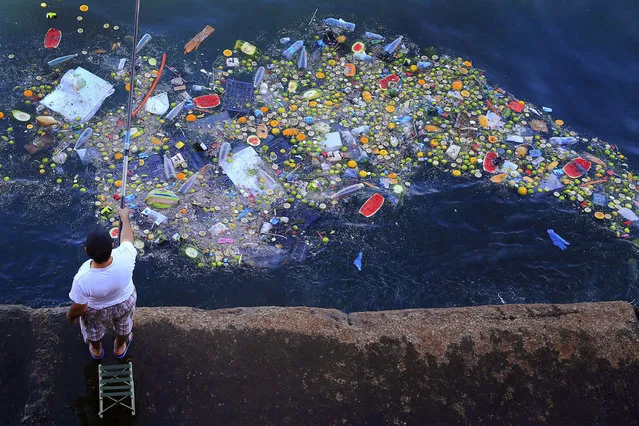 A man holds a fishing rod as floating trash hits the coastline of the Mediterranean Sea in Beirut, Lebanon, Thursday, September 29, 2016. (Photo by Hassan Ammar/AP Photo)